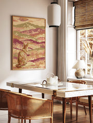 Stylised cat looking at a layered mountain landscape print with tapestry texture in pink, green, in a styled room mockup