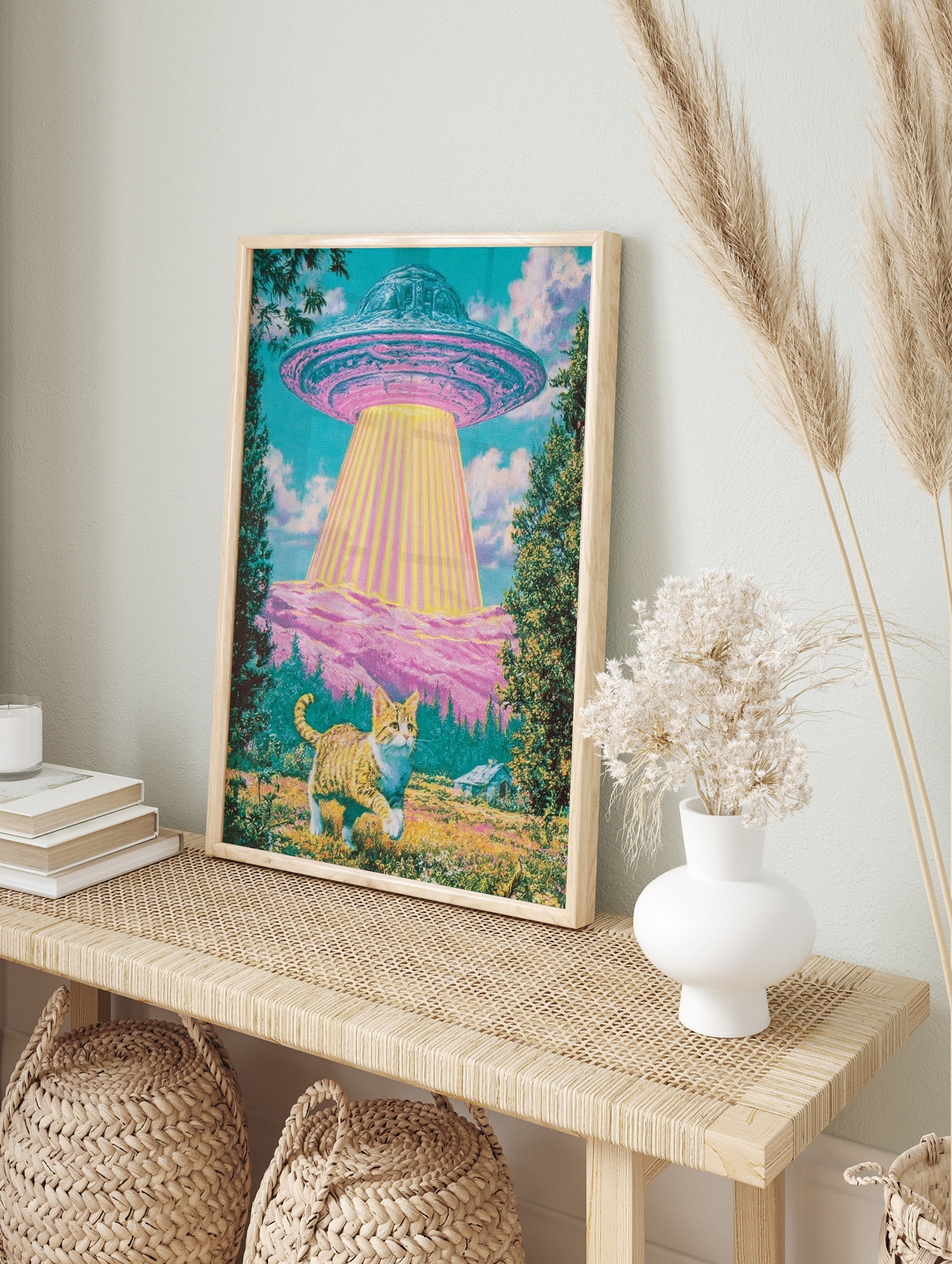Surreal art print of a ginger cat standing in a meadow looking up at a glowing UFO above pink, in an alternate framed mockup