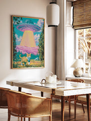 Surreal art print of a ginger cat standing in a meadow looking up at a glowing UFO above pink hills, in a styled room mockup