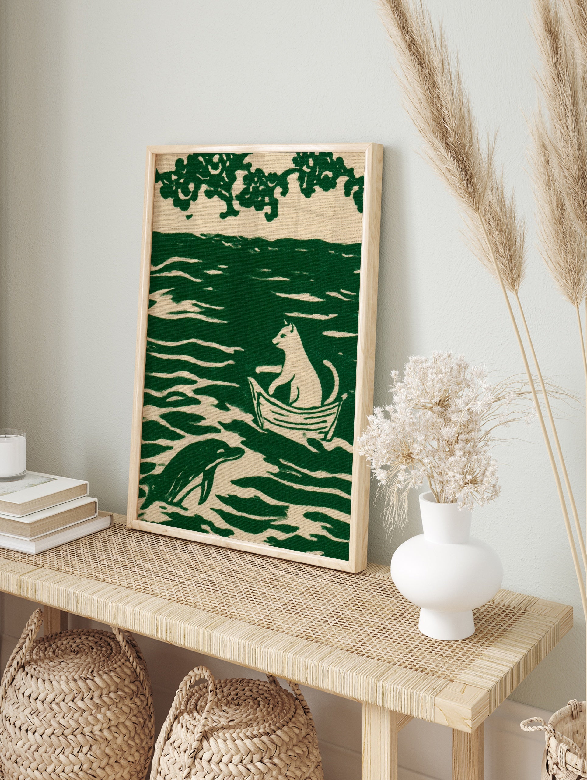 Illustration of a cat sitting in a boat on wavy water with a dolphin, printed in green and, in an alternate framed mockup