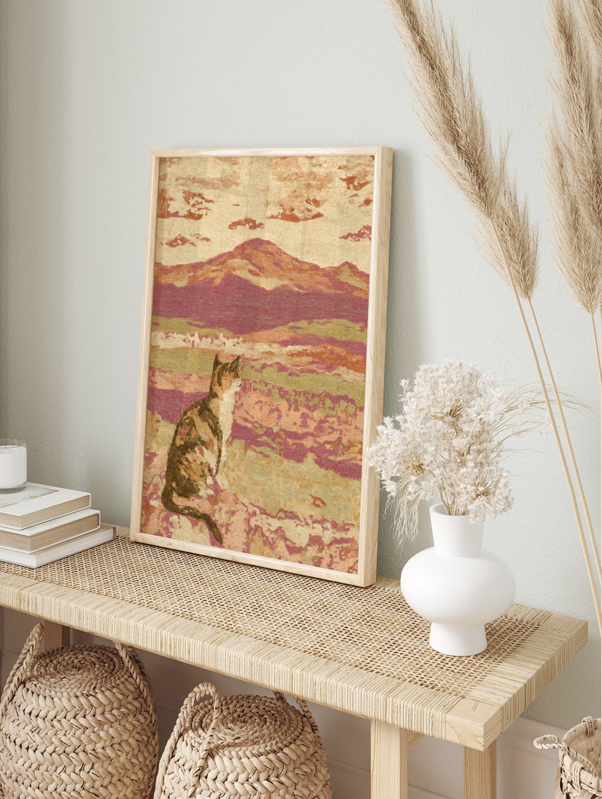 Impressionistic art print of a calico cat sitting in a landscape with hills and clouds, in an alternate framed mockup