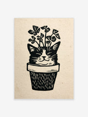 Linocut style illustration of a cat face emerging from a plant pot with clover leaves, black and white print