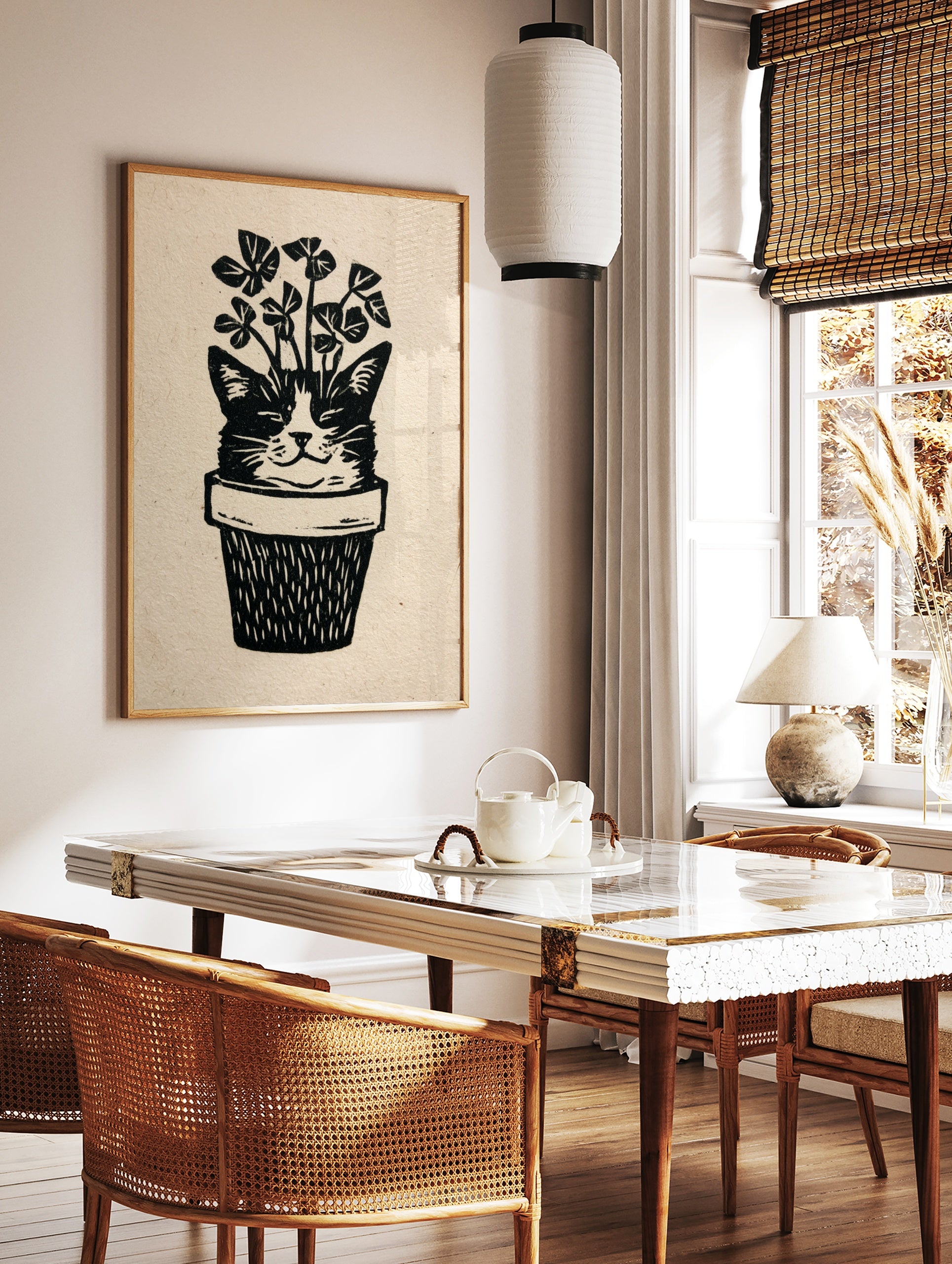 Linocut style illustration of a cat face emerging from a plant pot with clover leaves, black and, in a styled room mockup