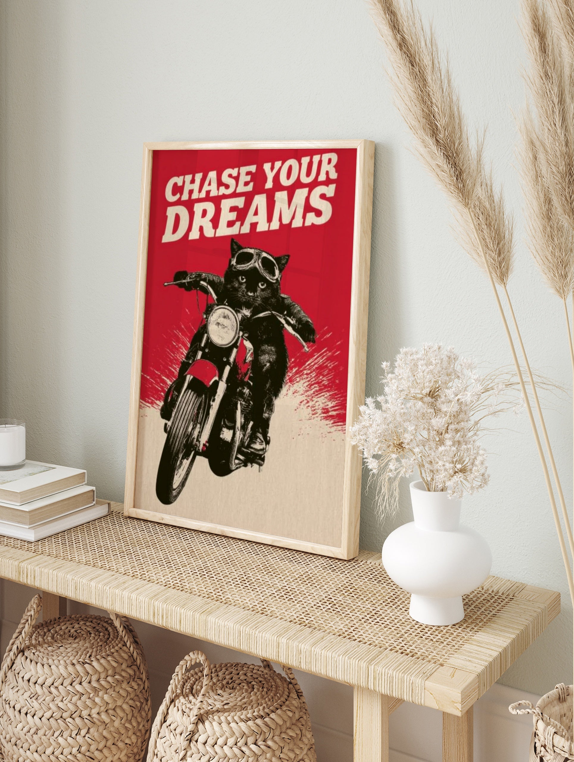Black cat wearing motorcycle goggles on a bike with red background and the text Chase Your, in an alternate framed mockup