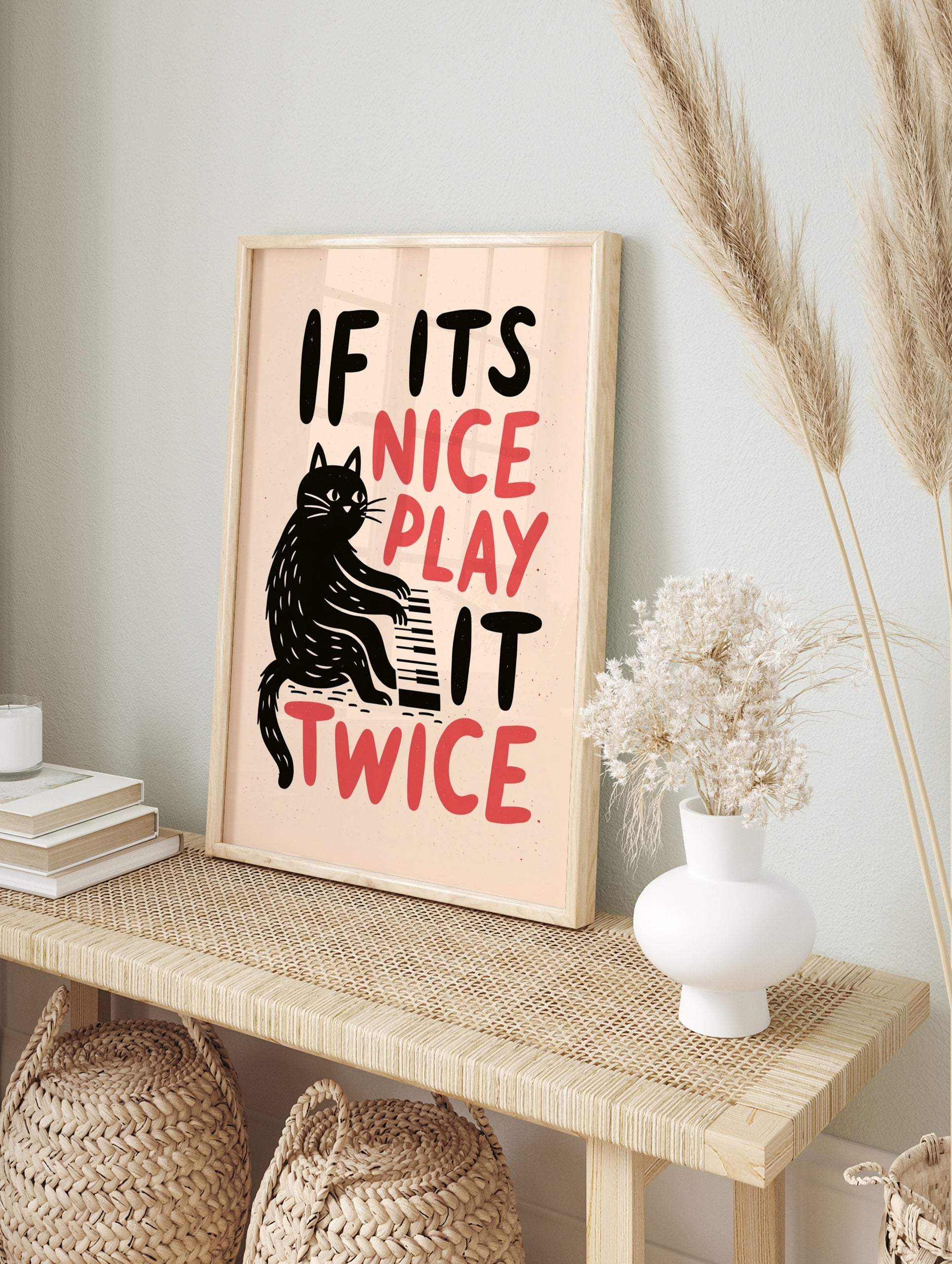 Black cat playing a piano illustration with the words IF ITS NICE PLAY IT TWICE in black and, in an alternate framed mockup