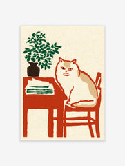 Illustrative print of a white and tan cat on a red chair next to a table with a green plant and papers