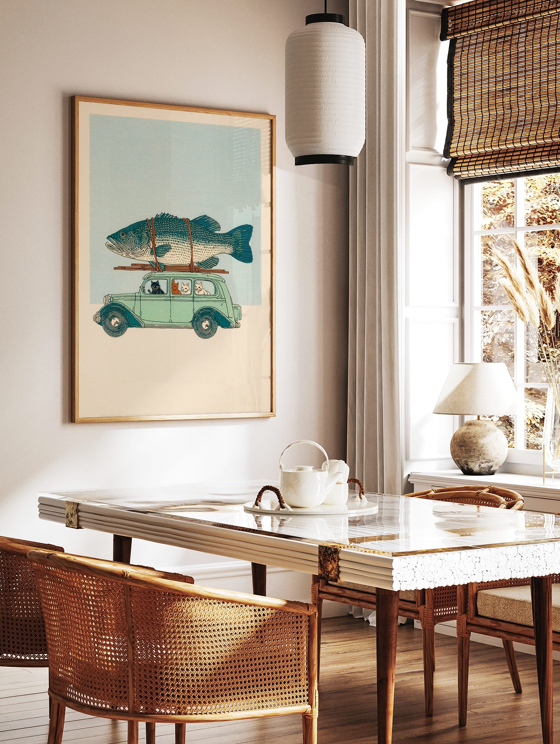 Illustrative print of cats driving a light green vintage car with a large teal fish on the roof, in a styled room mockup