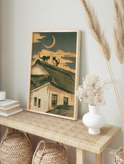 Two cats sitting on a traditional tiled roof under a crescent moon in an illustrative, in an alternate framed mockup