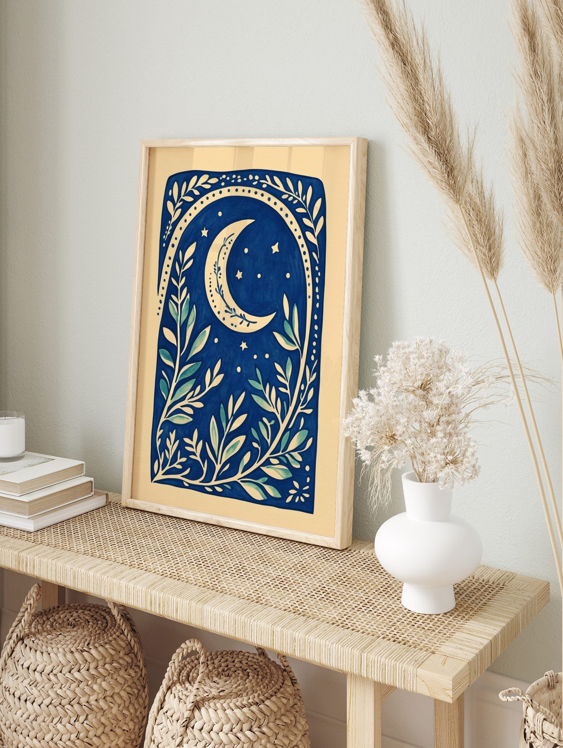 Illustrative deep blue botanical print with a cream crescent moon, stars, and leafy branches, in an alternate framed mockup