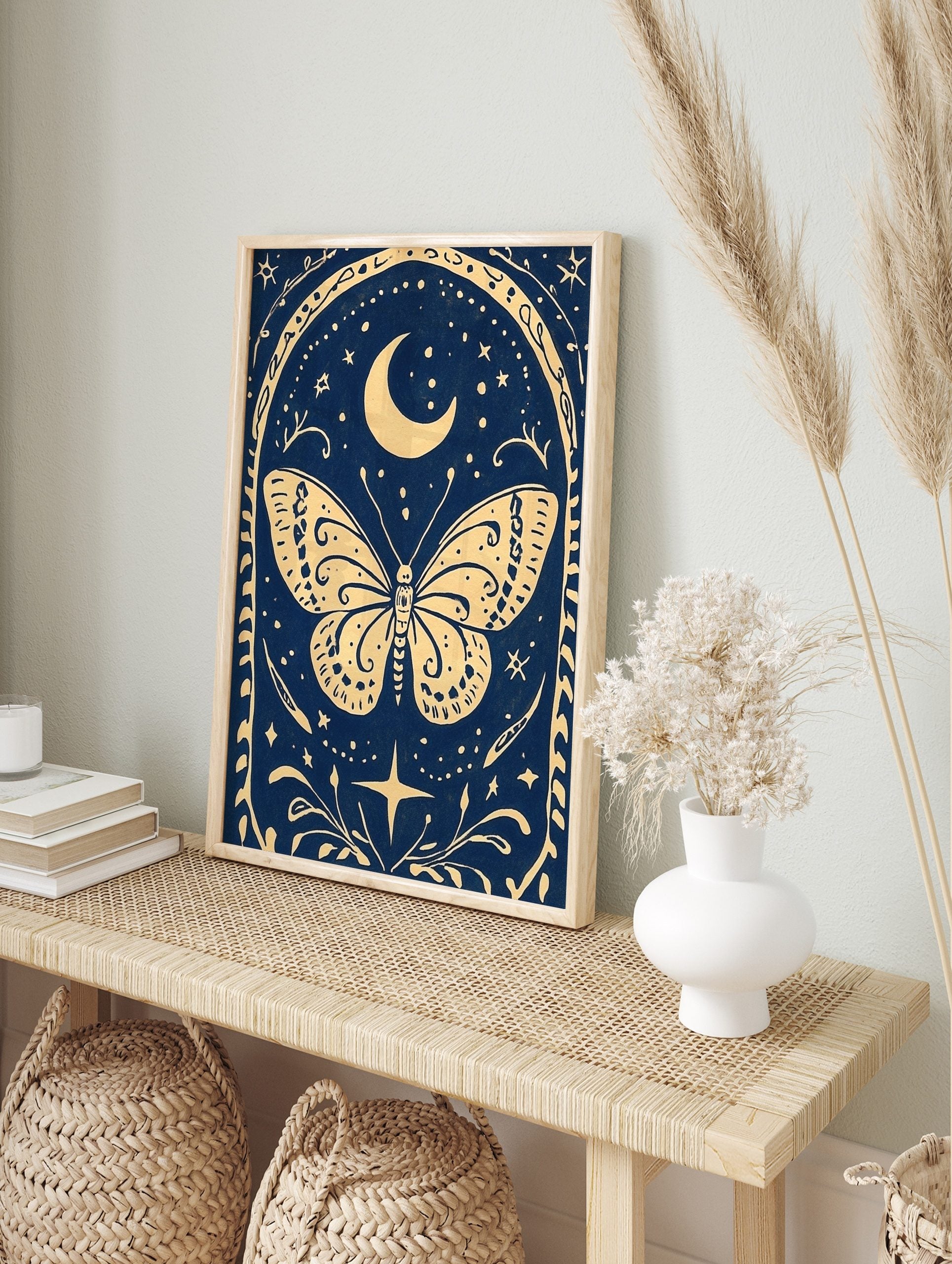 Illustrative celestial butterfly wall art with crescent moon, stars, and ornate border on a, in an alternate framed mockup
