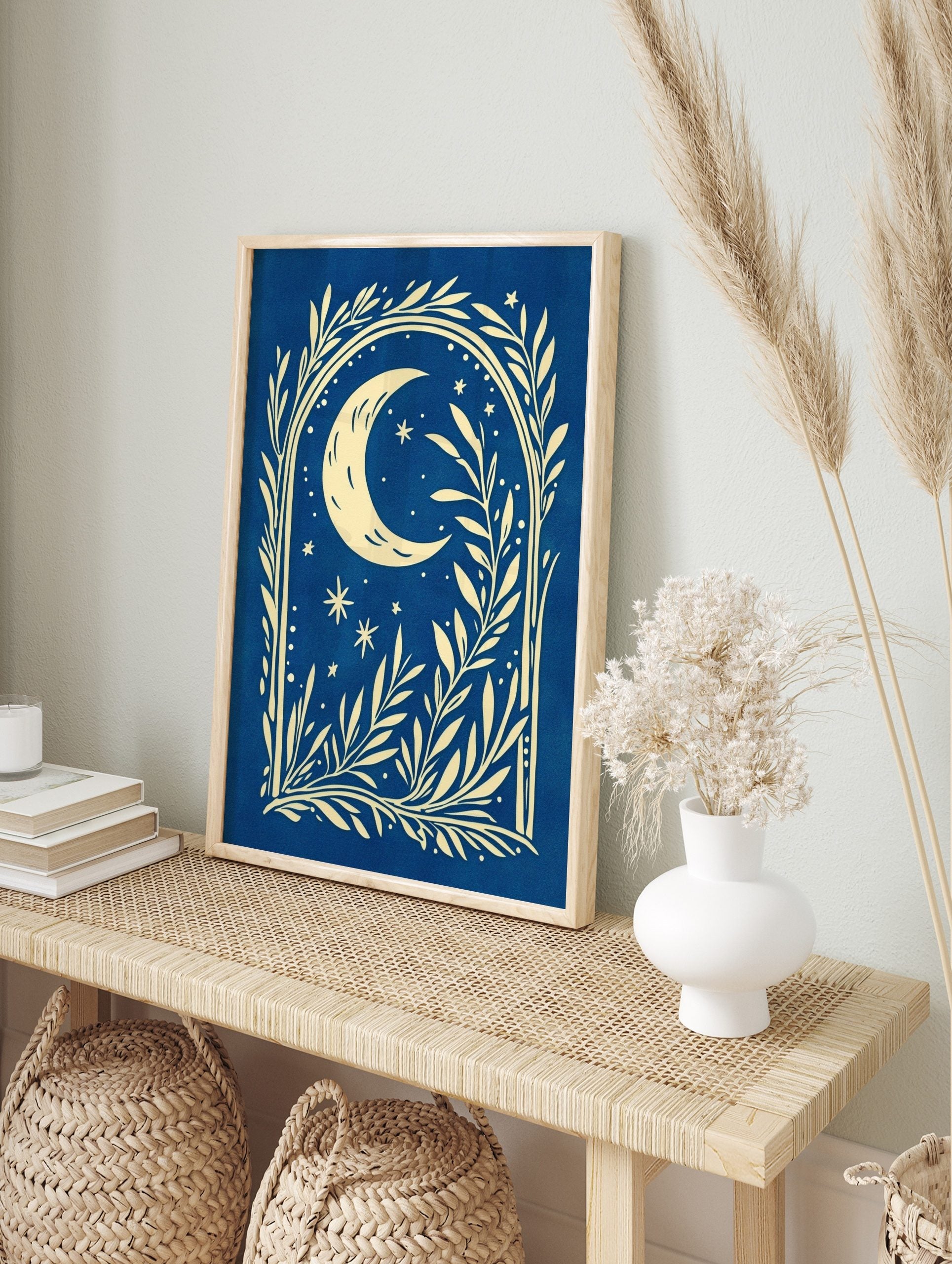 Illustrative cream crescent moon and stars with botanical foliage on a deep blue background, in an alternate framed mockup