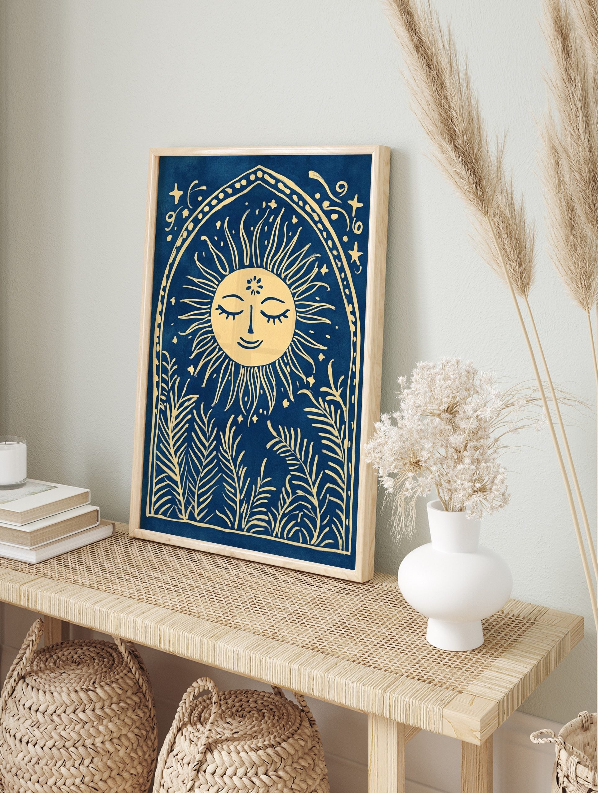 Illustrative print of a smiling sun with leafy plants in an arched frame on a blue background, in an alternate framed mockup