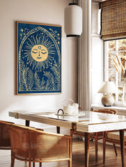 Illustrative print of a smiling sun with leafy plants in an arched frame on a blue background, in a styled room mockup