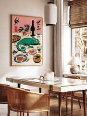 Green chameleon on a table with Japanese calligraphy, bottle, plant, and plates of food on a pink, in a styled room mockup