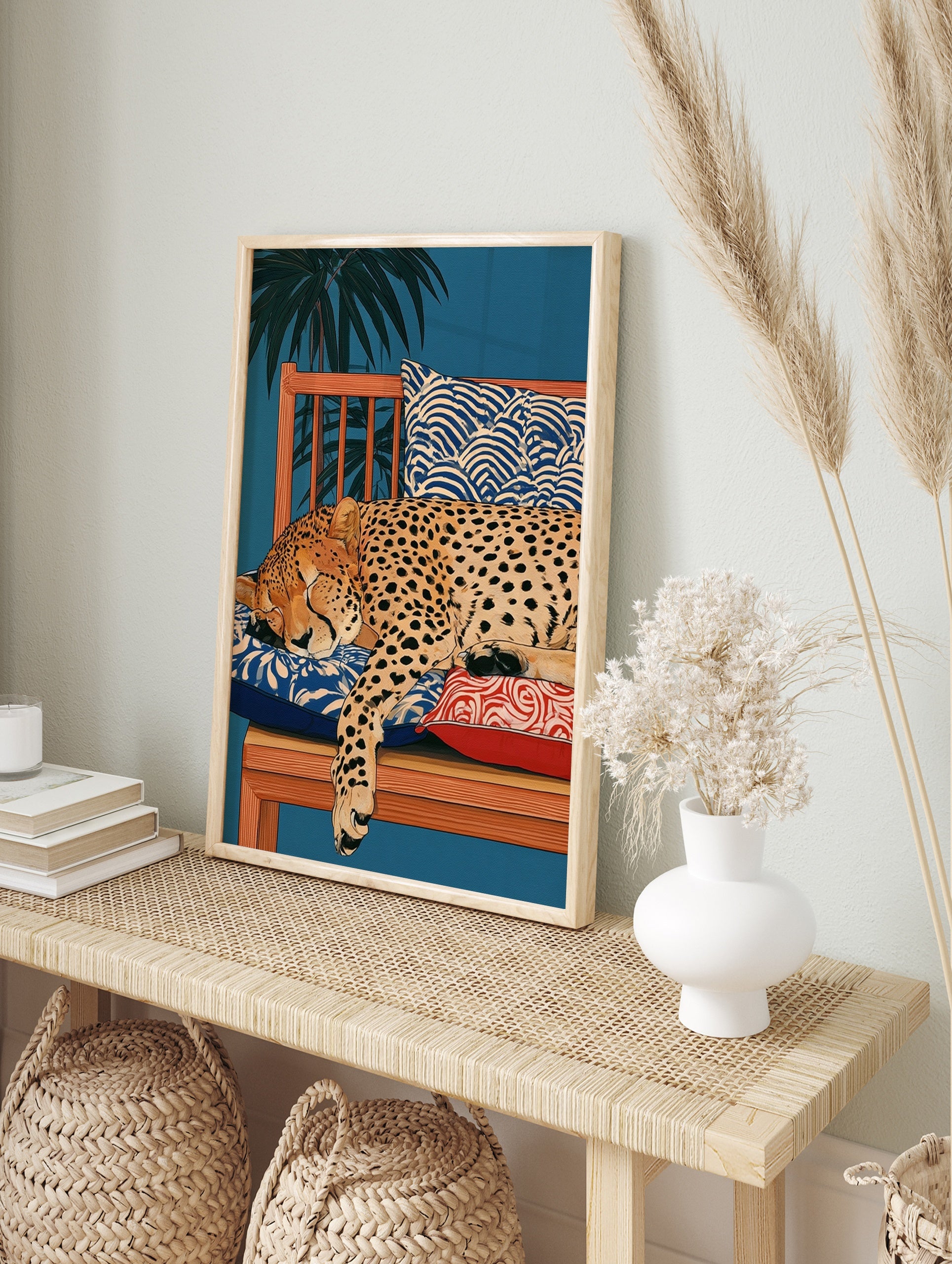 Illustration of a sleeping cheetah on a wooden bench with patterned cushions and palm leaves, in an alternate framed mockup
