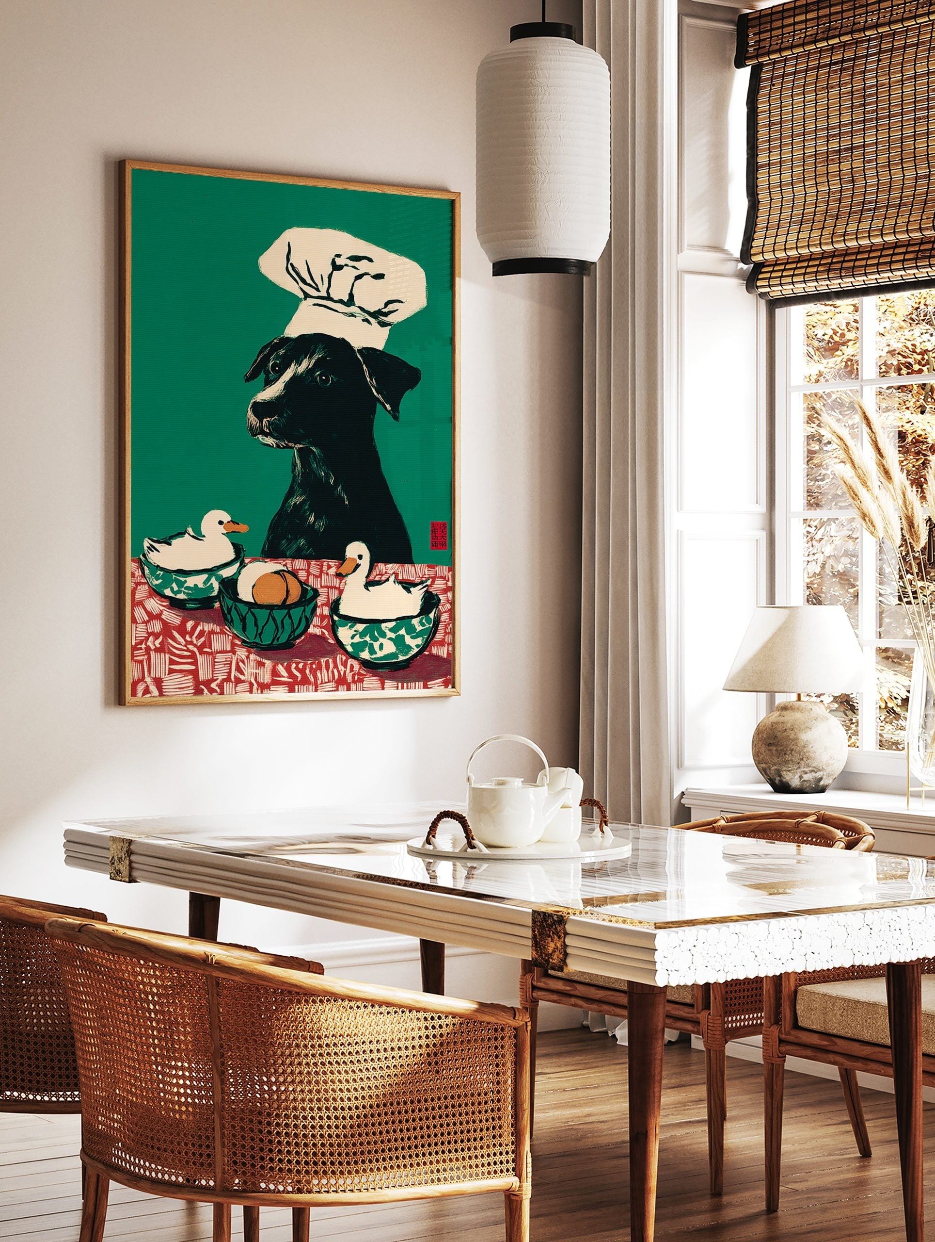 Illustrative wall art print of a black dog in a chef's hat with two ducks and eggs on a red and, in a styled room mockup