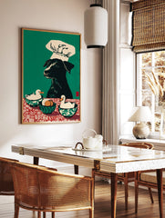 Illustrative wall art print of a black dog in a chef's hat with two ducks and eggs on a red and, in a styled room mockup
