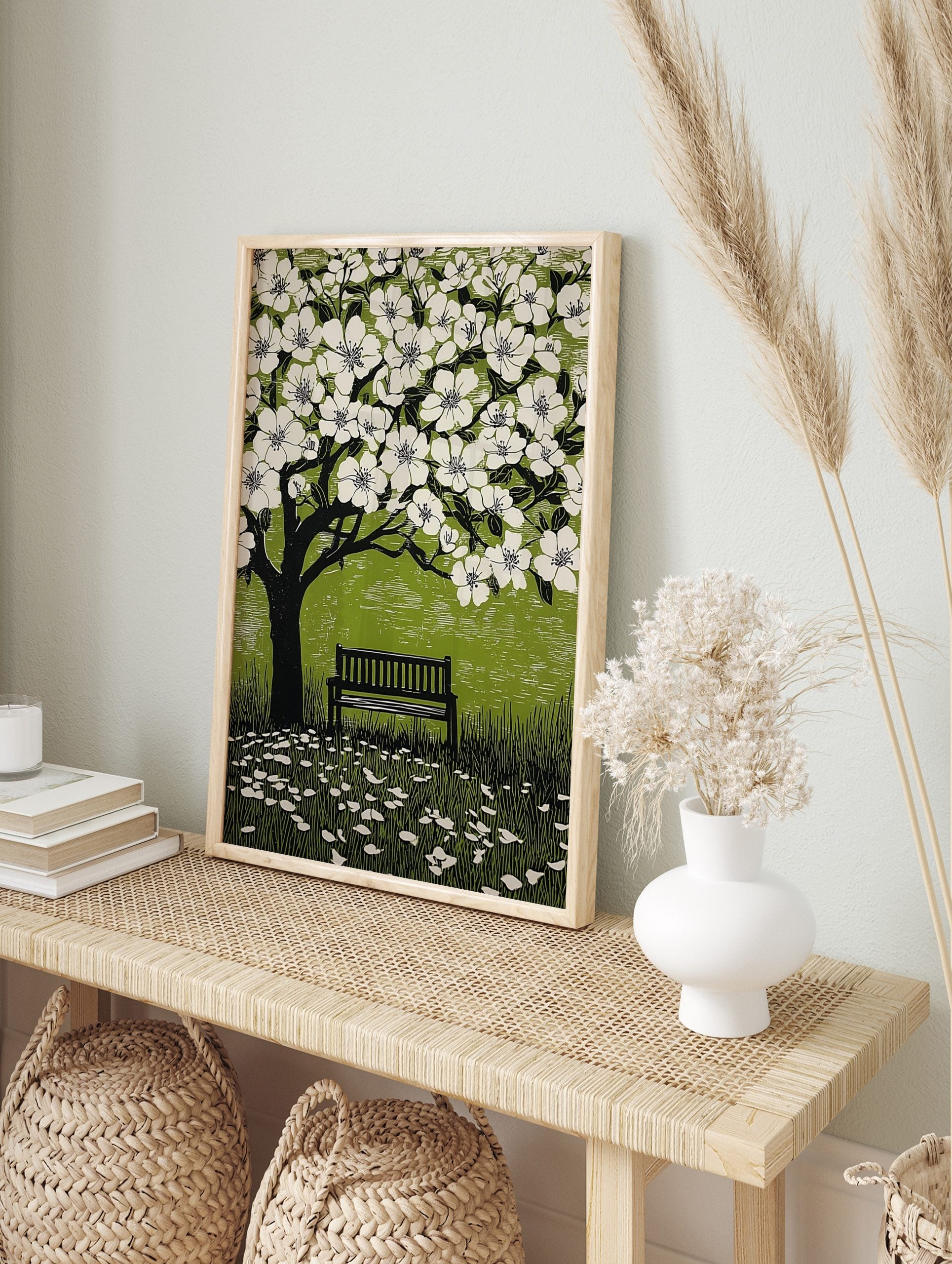 Illustrative linocut print of a black tree with white cherry blossoms, green background, and, in an alternate framed mockup