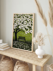 Illustrative linocut print of a black tree with white cherry blossoms, green background, and, in an alternate framed mockup