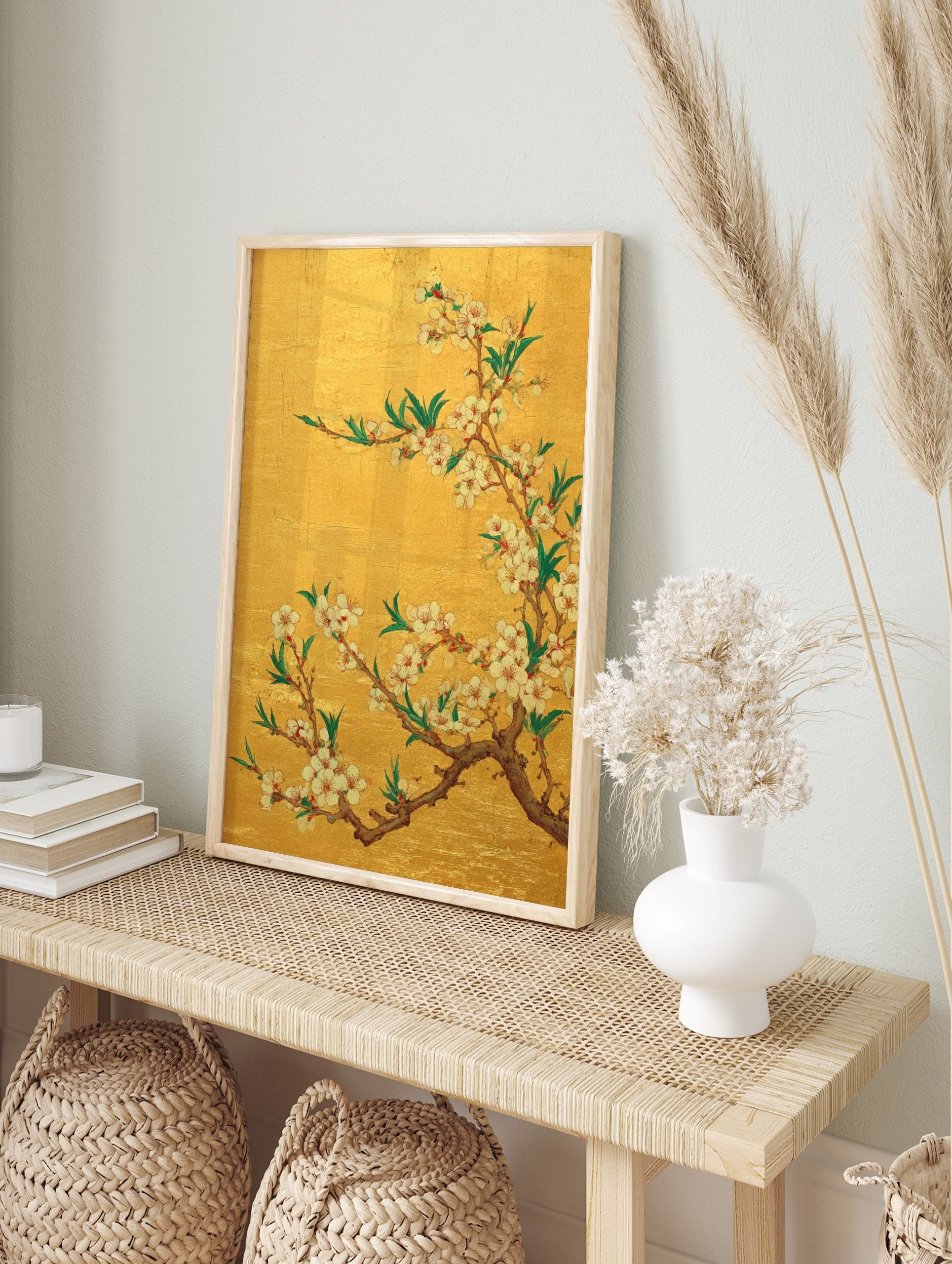 White and pink cherry blossom flowers on brown branches with green leaves against a gold, in an alternate framed mockup