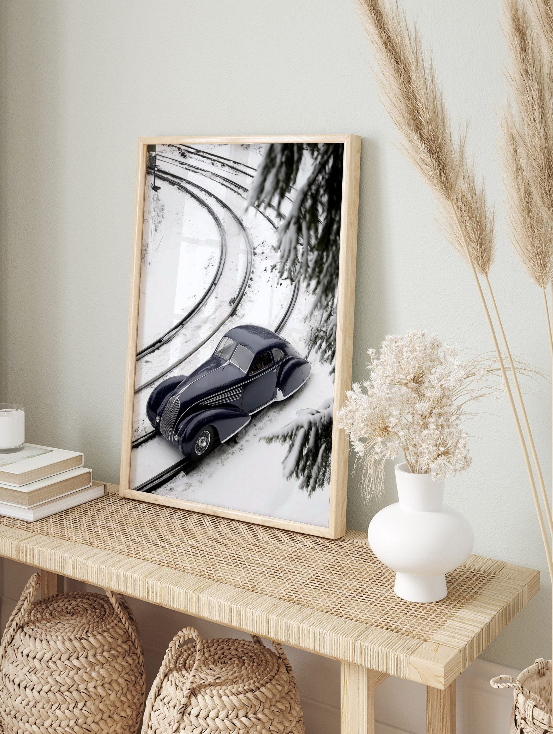 Navy blue classic car on snow-covered train tracks, high-angle view with pine branches and, in an alternate framed mockup