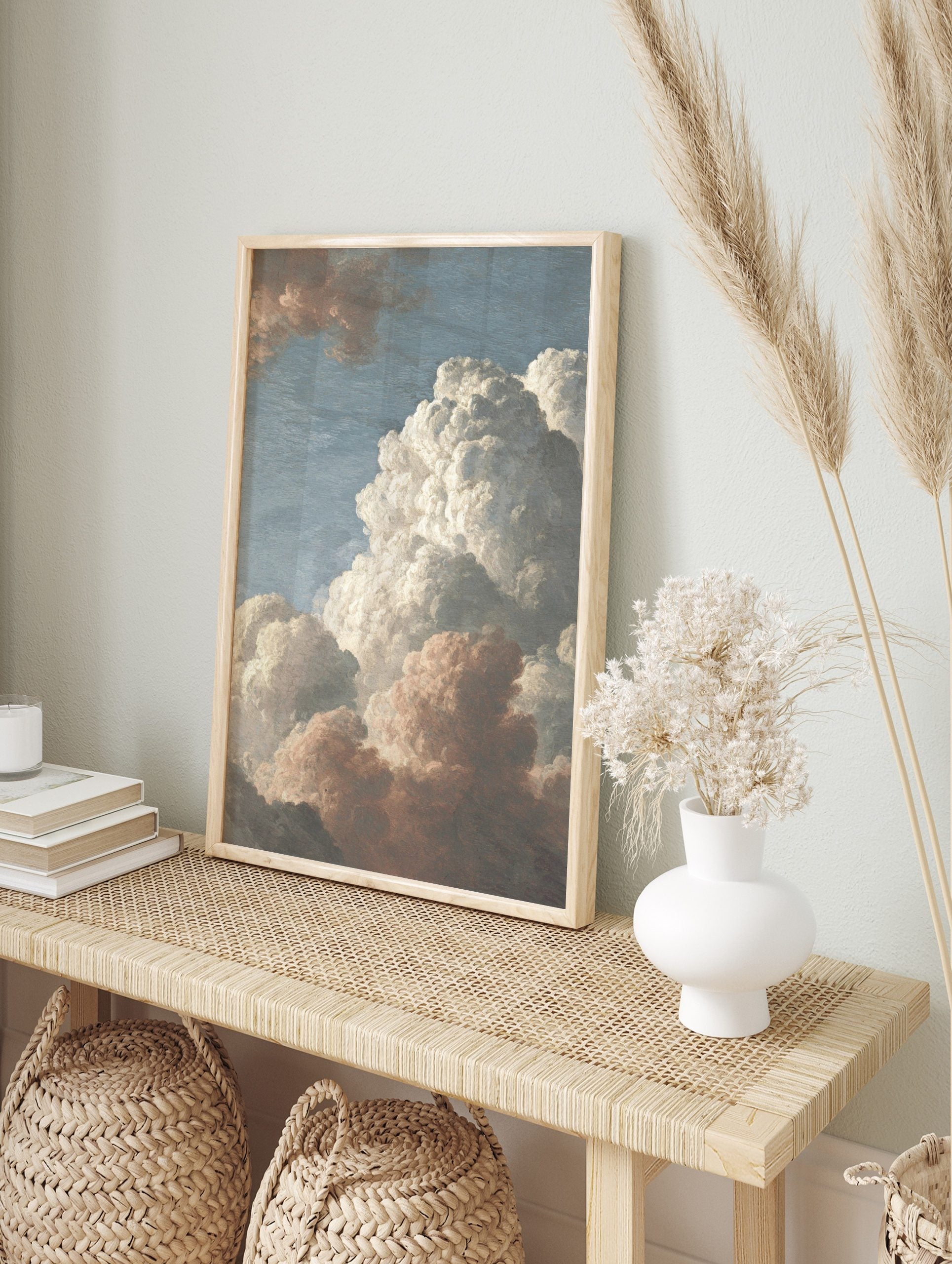 Detailed painting of voluminous white and reddish-brown cumulus clouds against a pale blue sky, in an alternate framed mockup