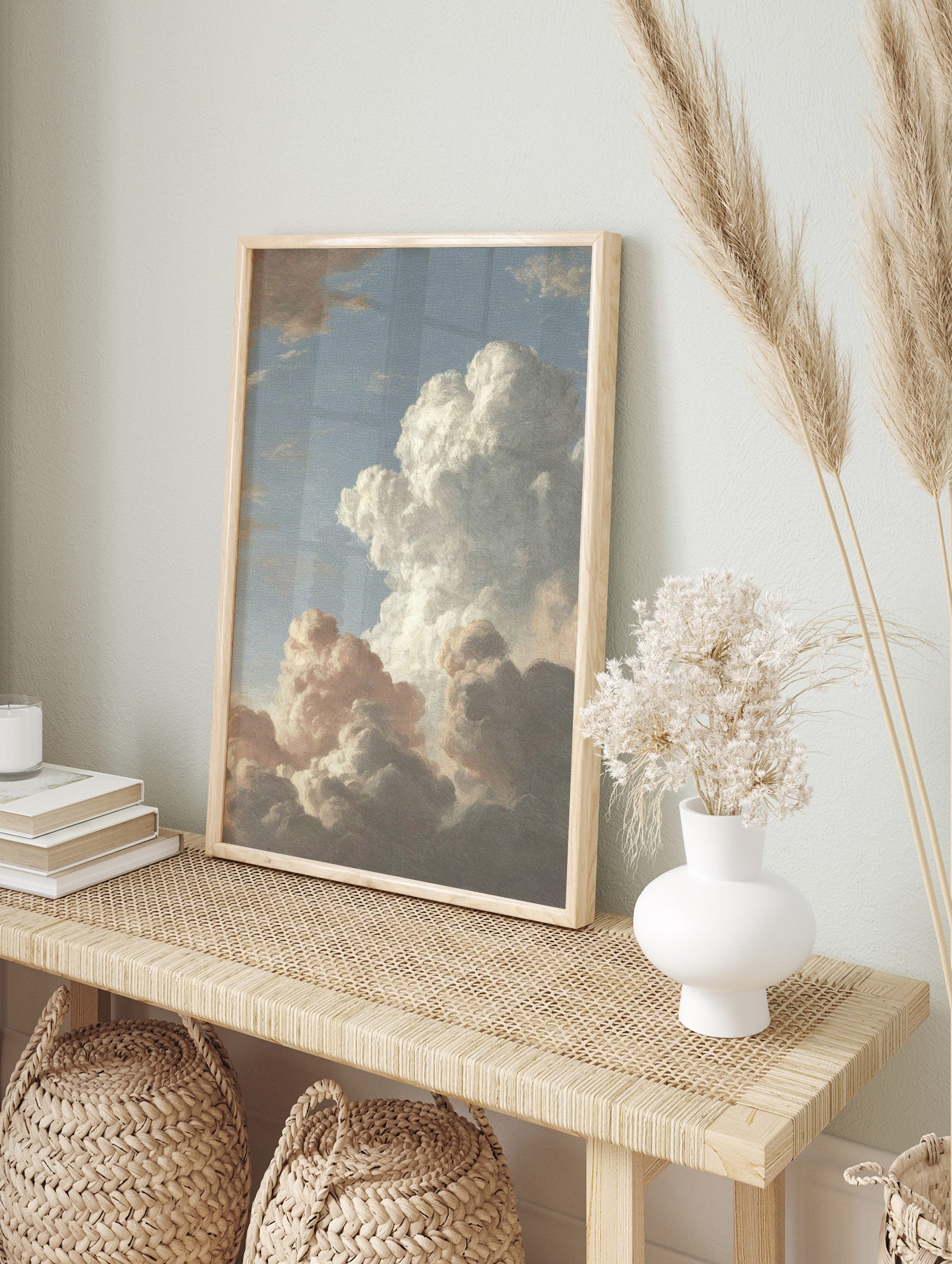 Dramatic cloud study painting with voluminous white and grey clouds against a soft blue sky, in an alternate framed mockup