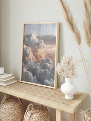 Aerial view of fluffy white and grey clouds with soft peachy light across a vast sky, in an alternate framed mockup