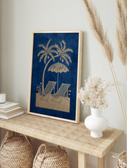 Golden palm tree, beach umbrella, and two striped deck chairs on a blue background in an, in an alternate framed mockup
