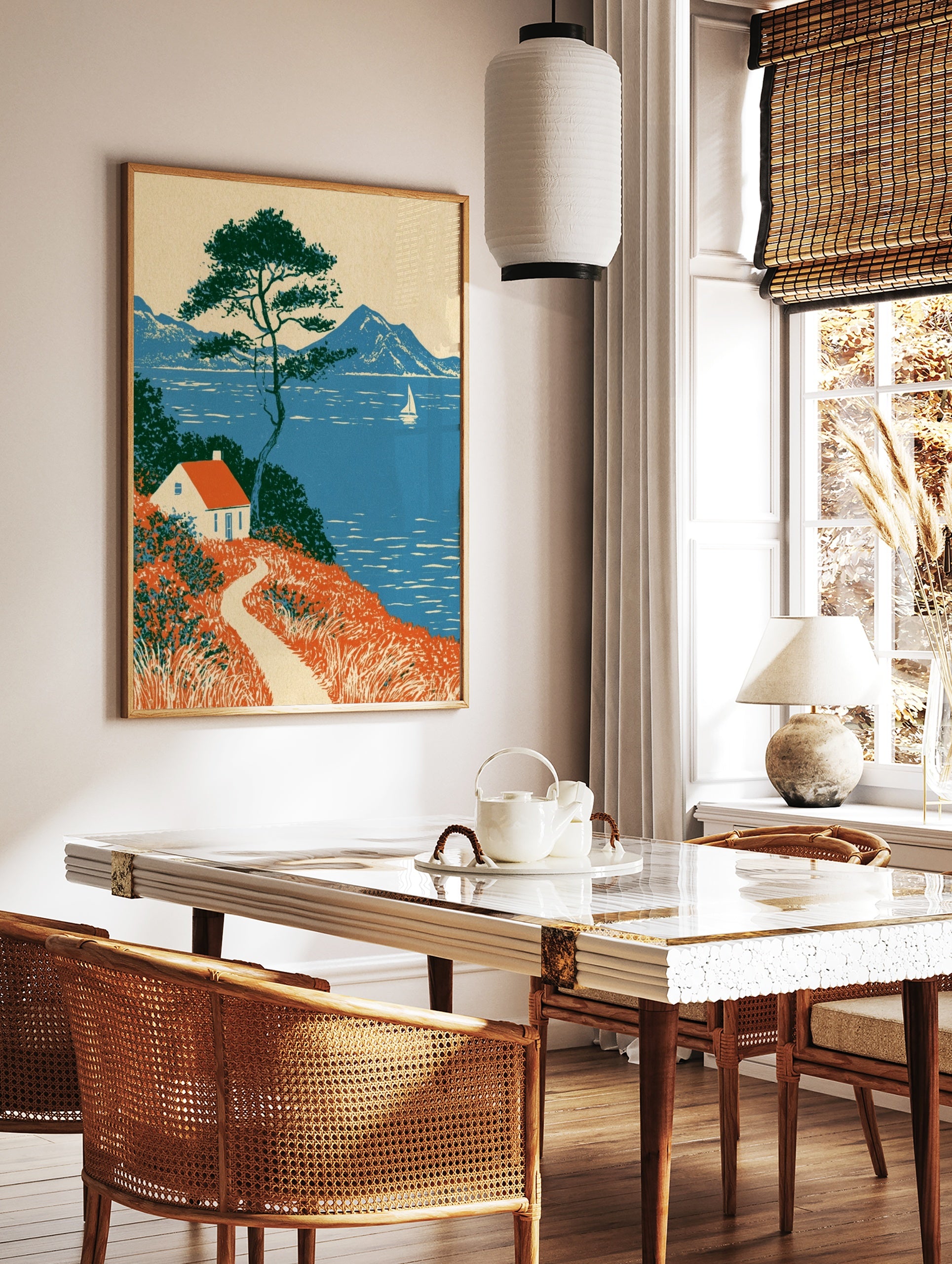 Coastal cottage wall art with red roof house, pine tree, and sailboat on blue sea landscape, in a styled room mockup
