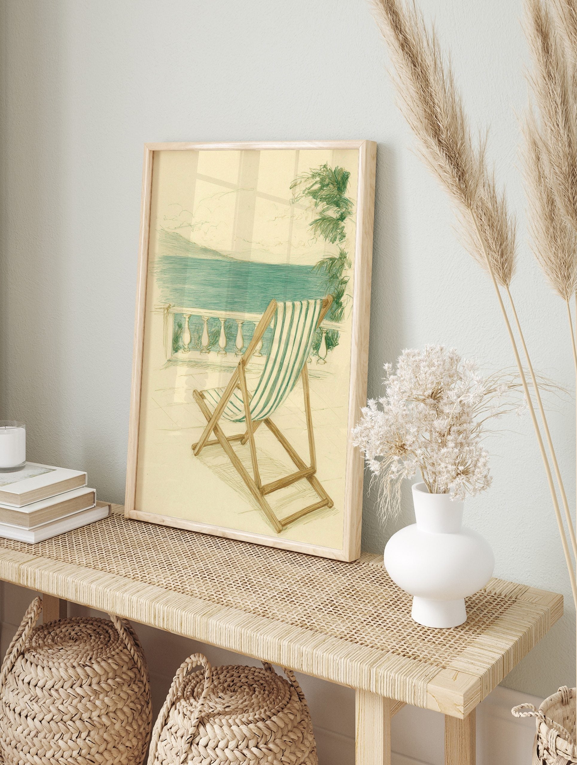 Illustrative print of green and white striped deckchair on balcony overlooking blue sea and, in an alternate framed mockup