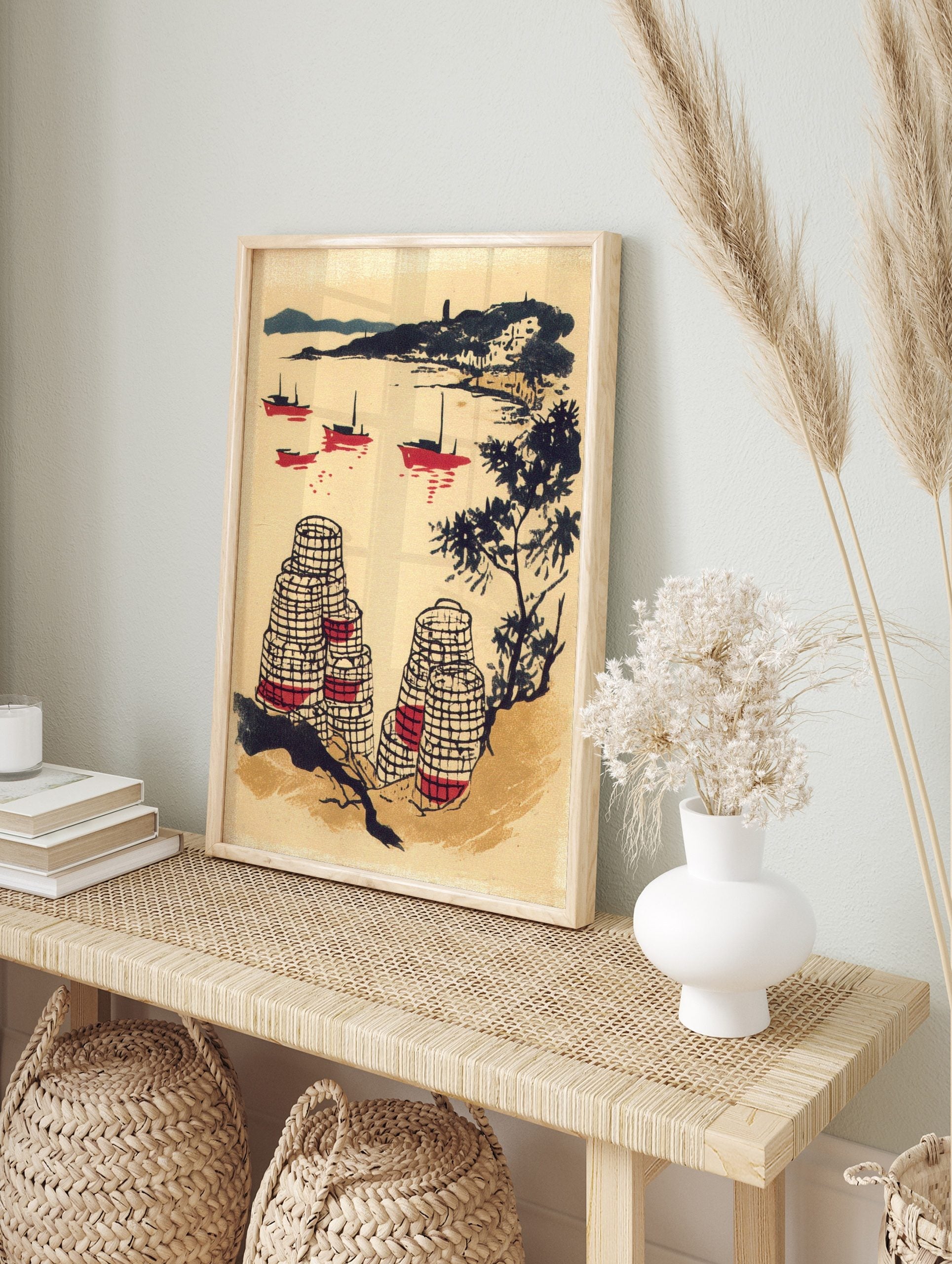 Illustrative coastal scene with red fishing boats, dark hills, and patterned lobster pots in, in an alternate framed mockup