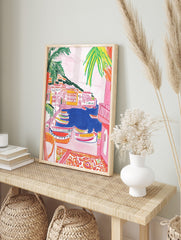 Colourful illustrative wall art of a coastal village with boats in a blue harbour and palm, in an alternate framed mockup