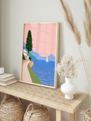 Minimalist coastal wall art featuring a white house, winding path, sailboat, and blue, in an alternate framed mockup