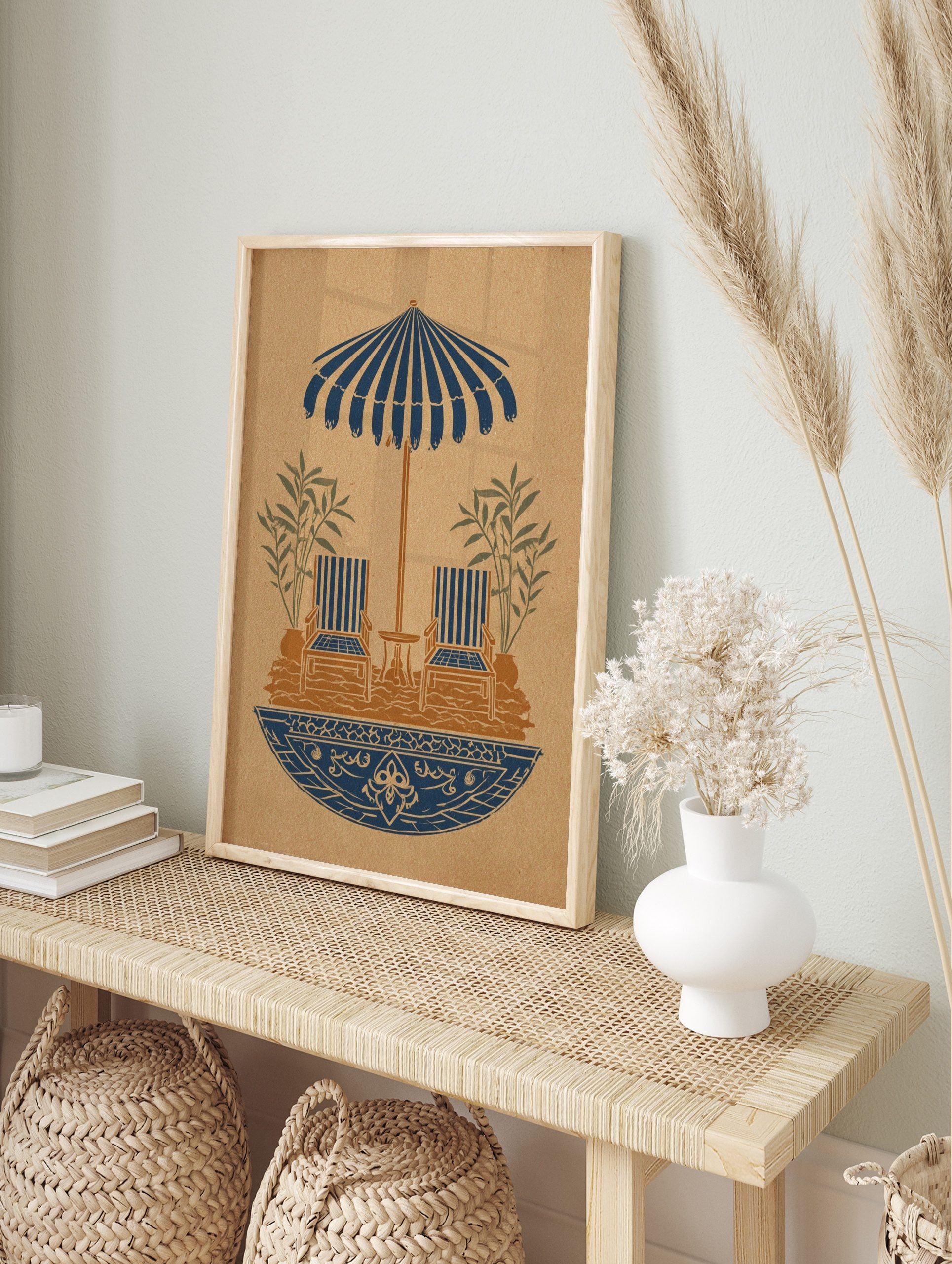 Illustrative print of striped parasol, two lounge chairs, table, plants in blue and brown on, in an alternate framed mockup