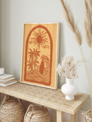 Illustrative coastal scene art print with sun, palm trees, surfboard in waves, within an arch, in an alternate framed mockup
