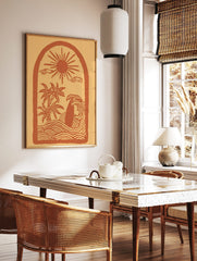 Illustrative coastal scene art print with sun, palm trees, surfboard in waves, within an arch frame, in a styled room mockup