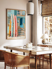 Colourful surfboards leaning against a light blue beach house with an open blue door and wooden, in a styled room mockup