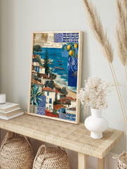 Coastal village scene with white and blue houses, red roofs, blue sea, boats, and blue tile, in an alternate framed mockup