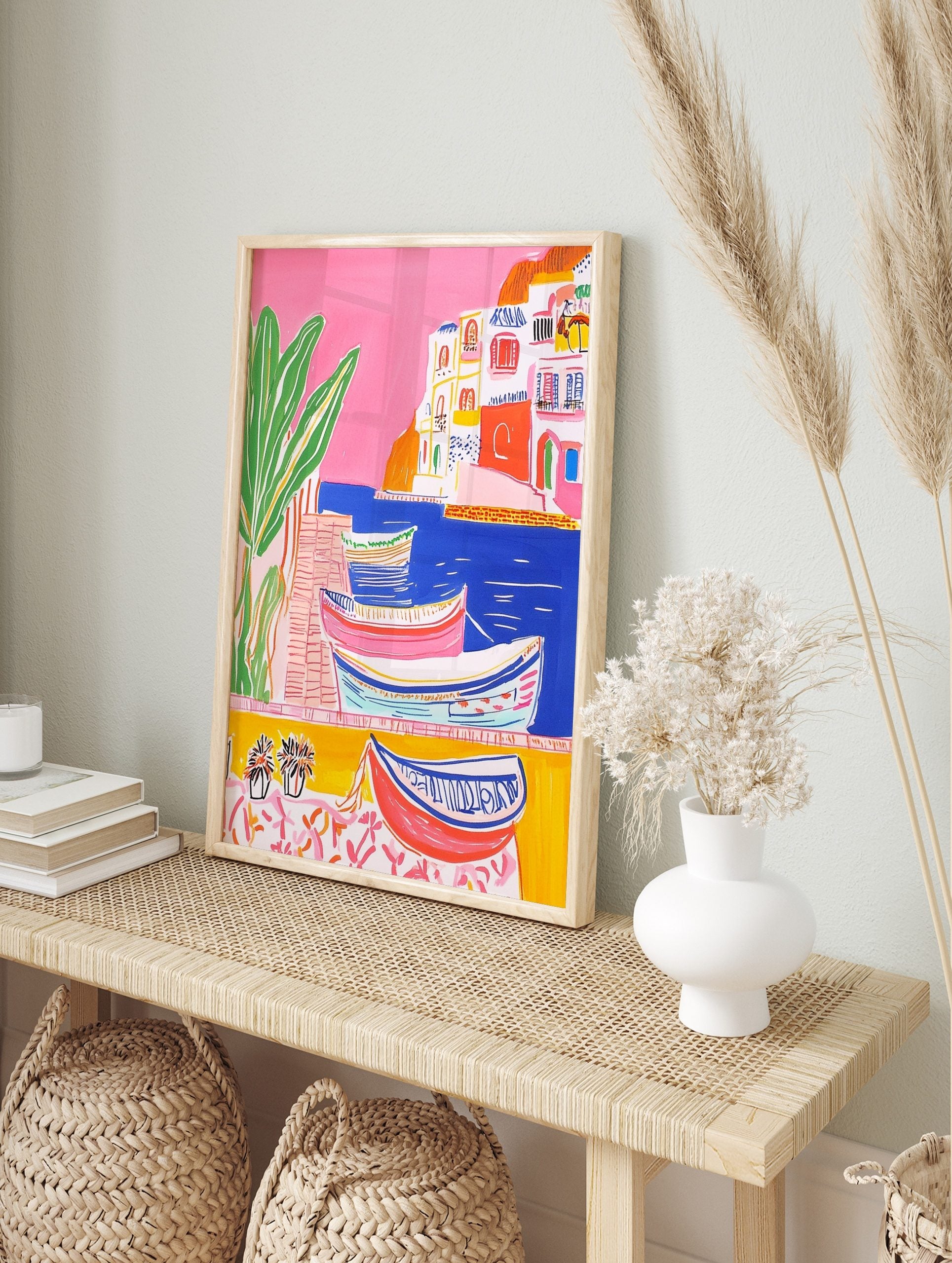 Colourful illustrative coastal town art print with boats in blue water, white buildings, and, in an alternate framed mockup
