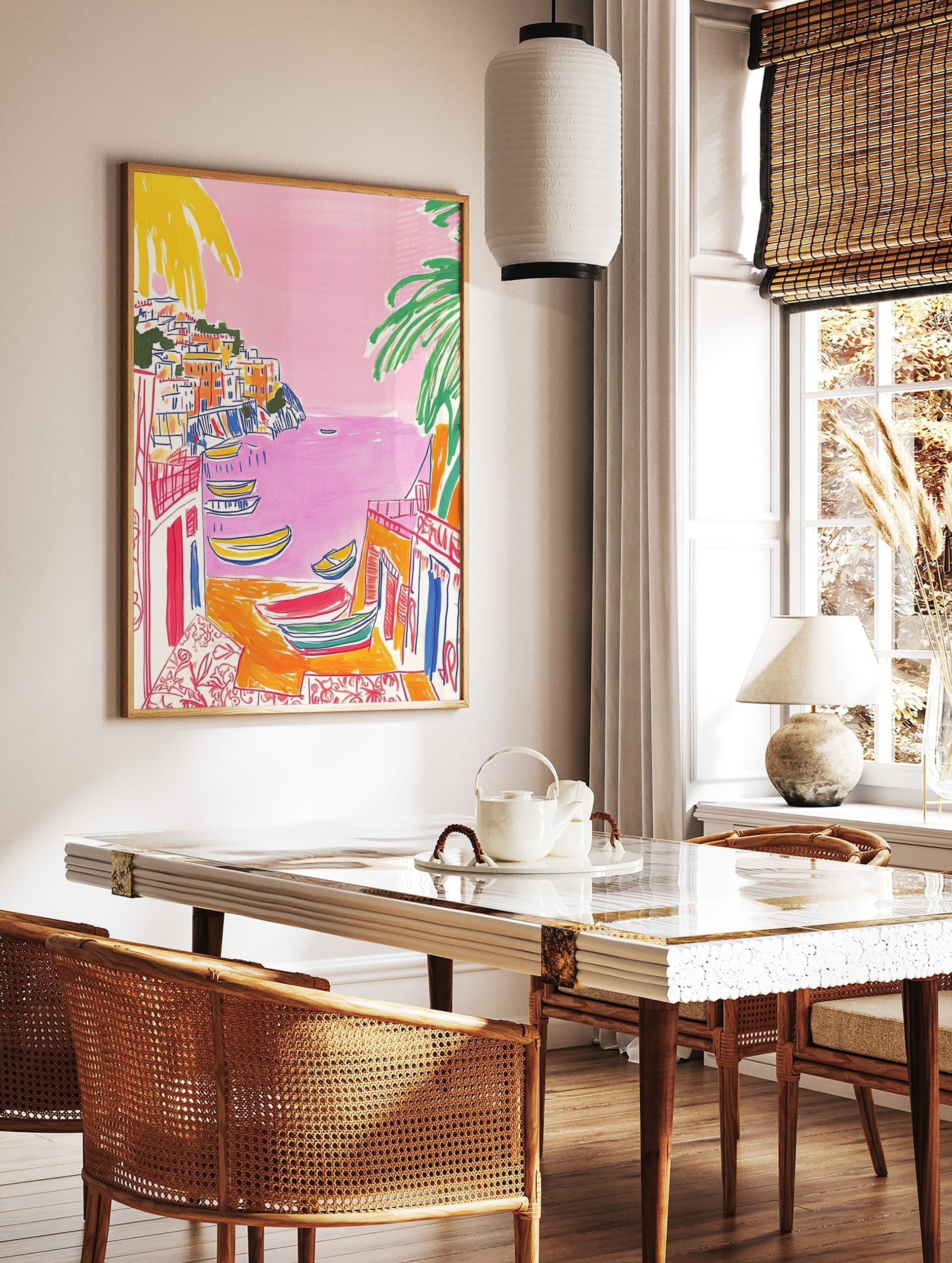 Illustrative print of a colourful coastal town with pink sea, yellow boats, and green palm trees, in a styled room mockup