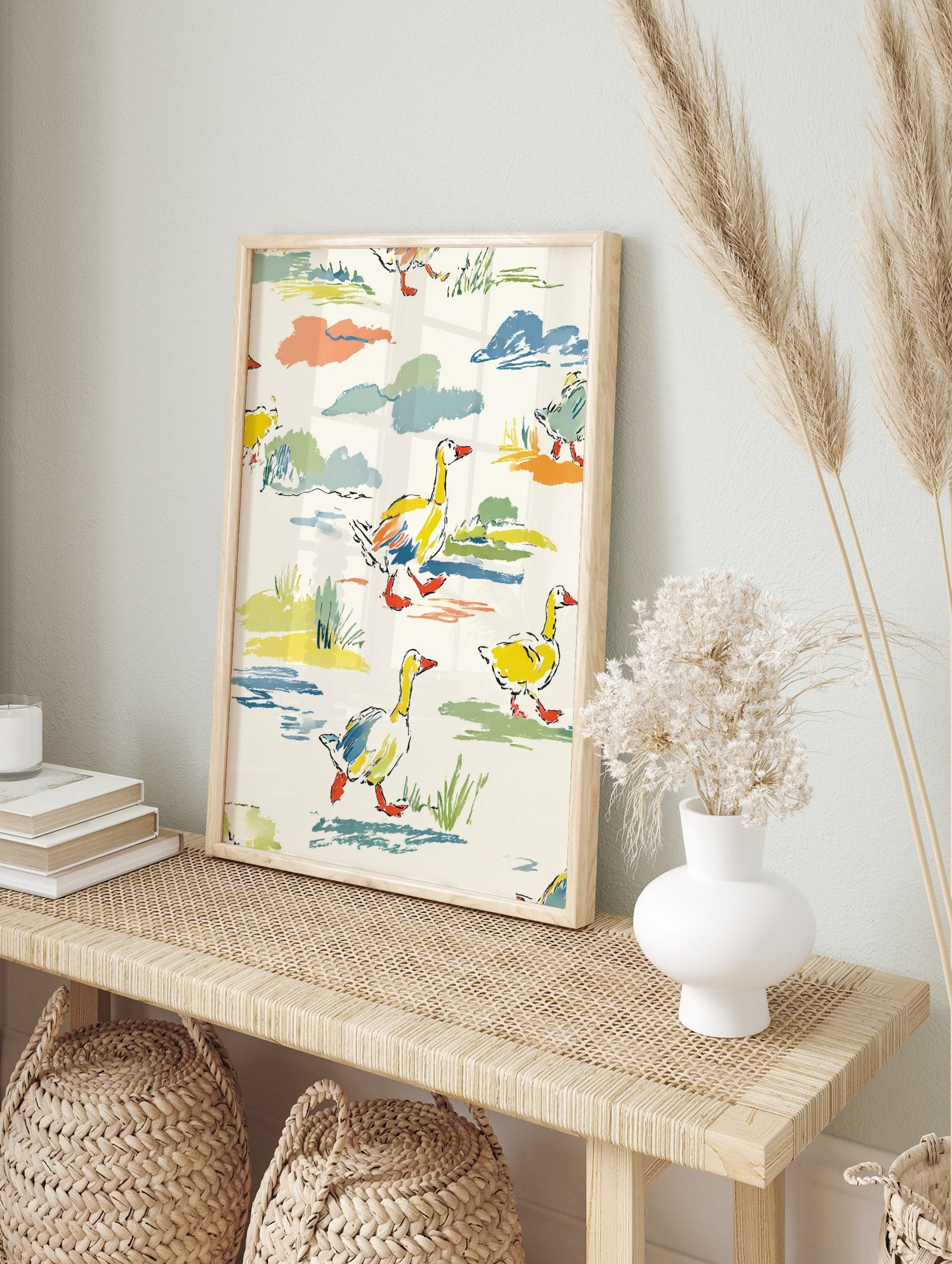 Colourful illustrative wall art print of yellow ducks with orange beaks walking through green, in an alternate framed mockup