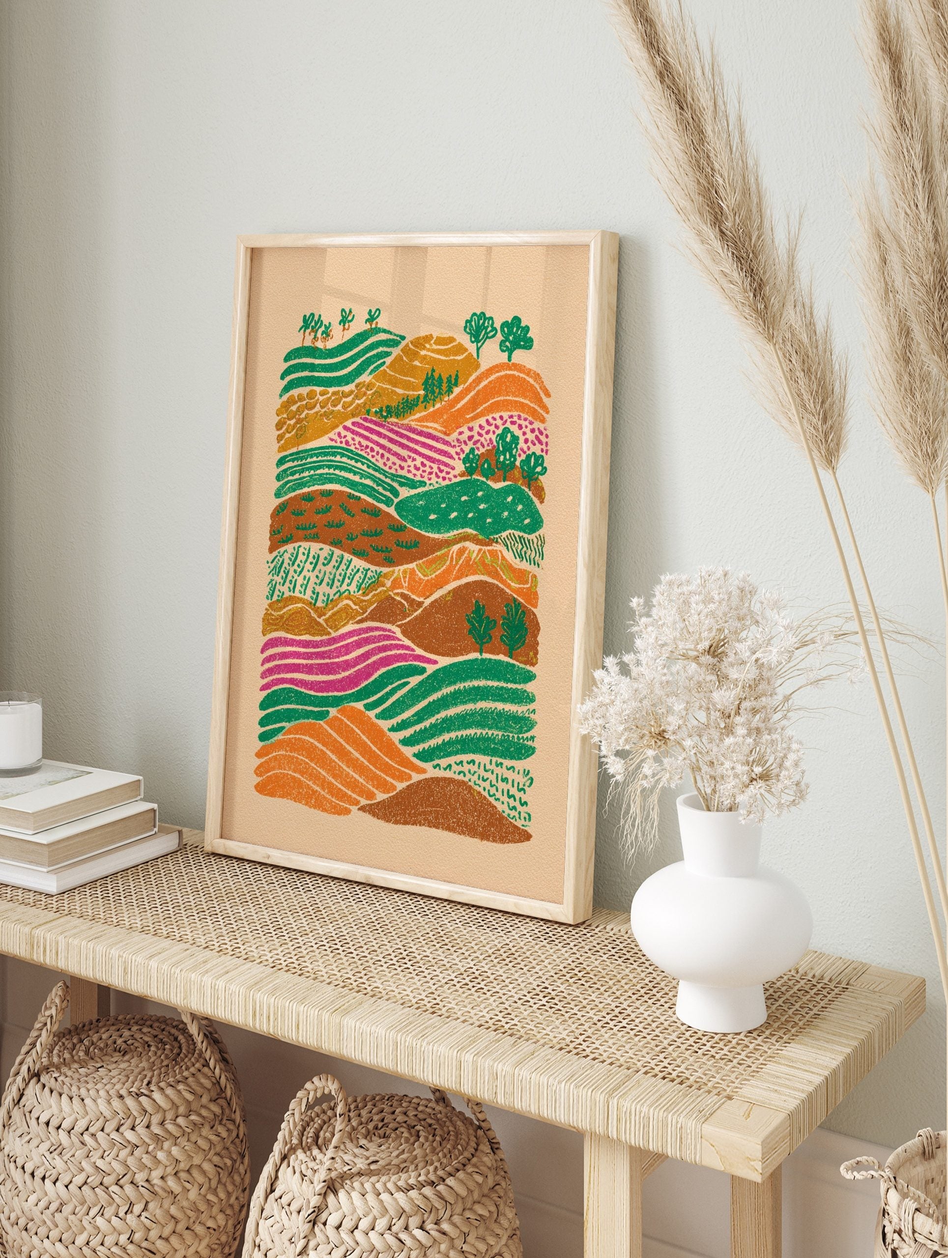 Colourful illustrative landscape art print with rolling hills, patterned green, orange, and, in an alternate framed mockup