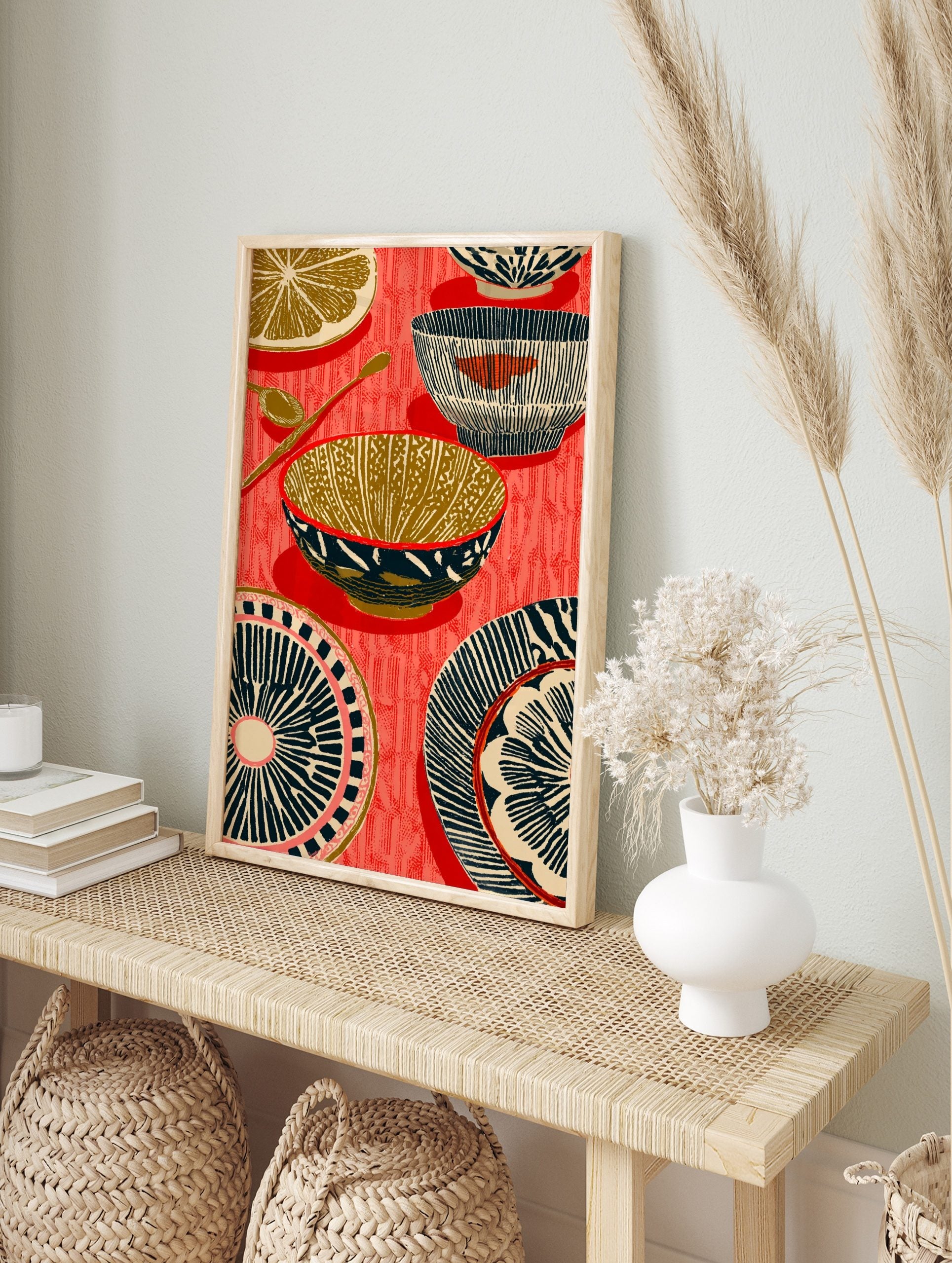 Illustrative kitchenware print with patterned bowls, plates, spoons, and a lemon slice on a, in an alternate framed mockup