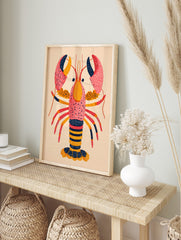 Colourful illustrative art print of a lobster with speckled pink, orange, red, and navy, in an alternate framed mockup