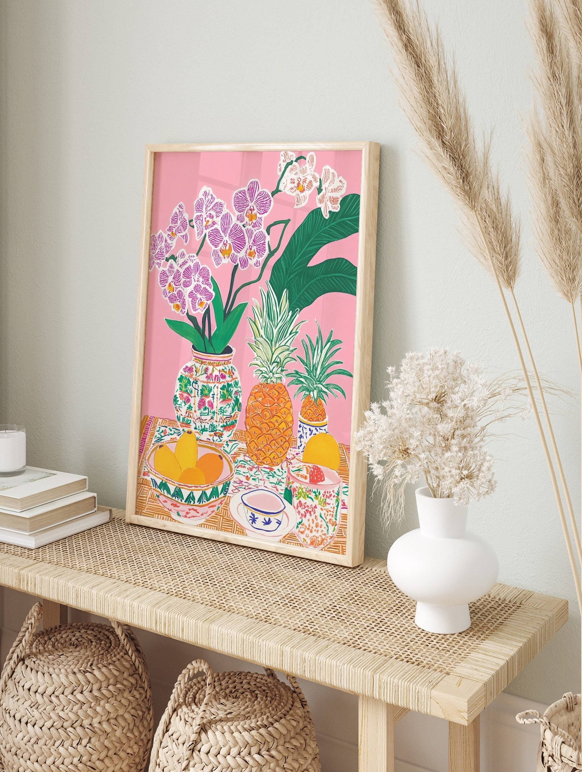 Colourful illustrative still life print with pink orchids, pineapples, mangoes, and patterned, in an alternate framed mockup