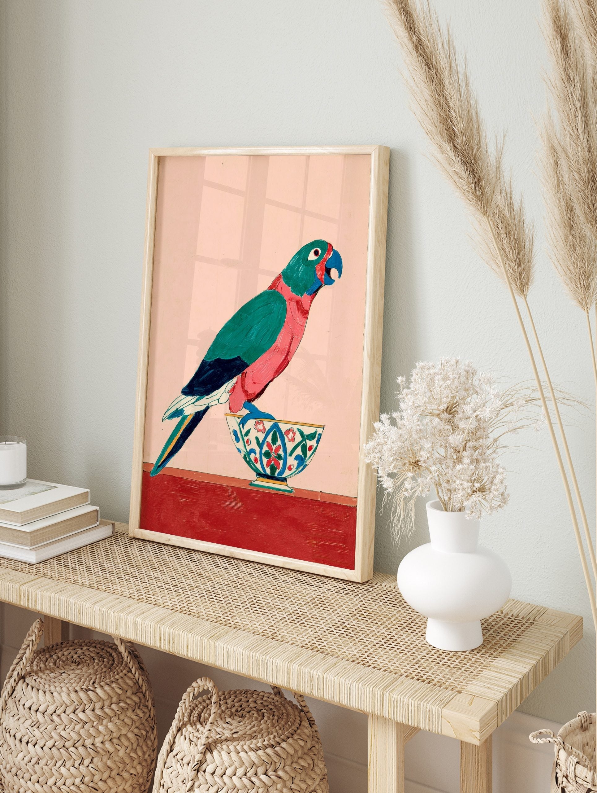 Colourful parrot with teal and pink feathers standing on a decorative bowl against a pale, in an alternate framed mockup