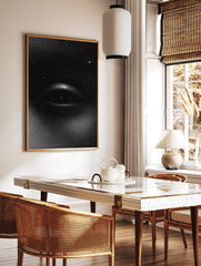 Monochrome stipple print of a cosmic eye with stars on a black background, unframed wall art, in a styled room mockup