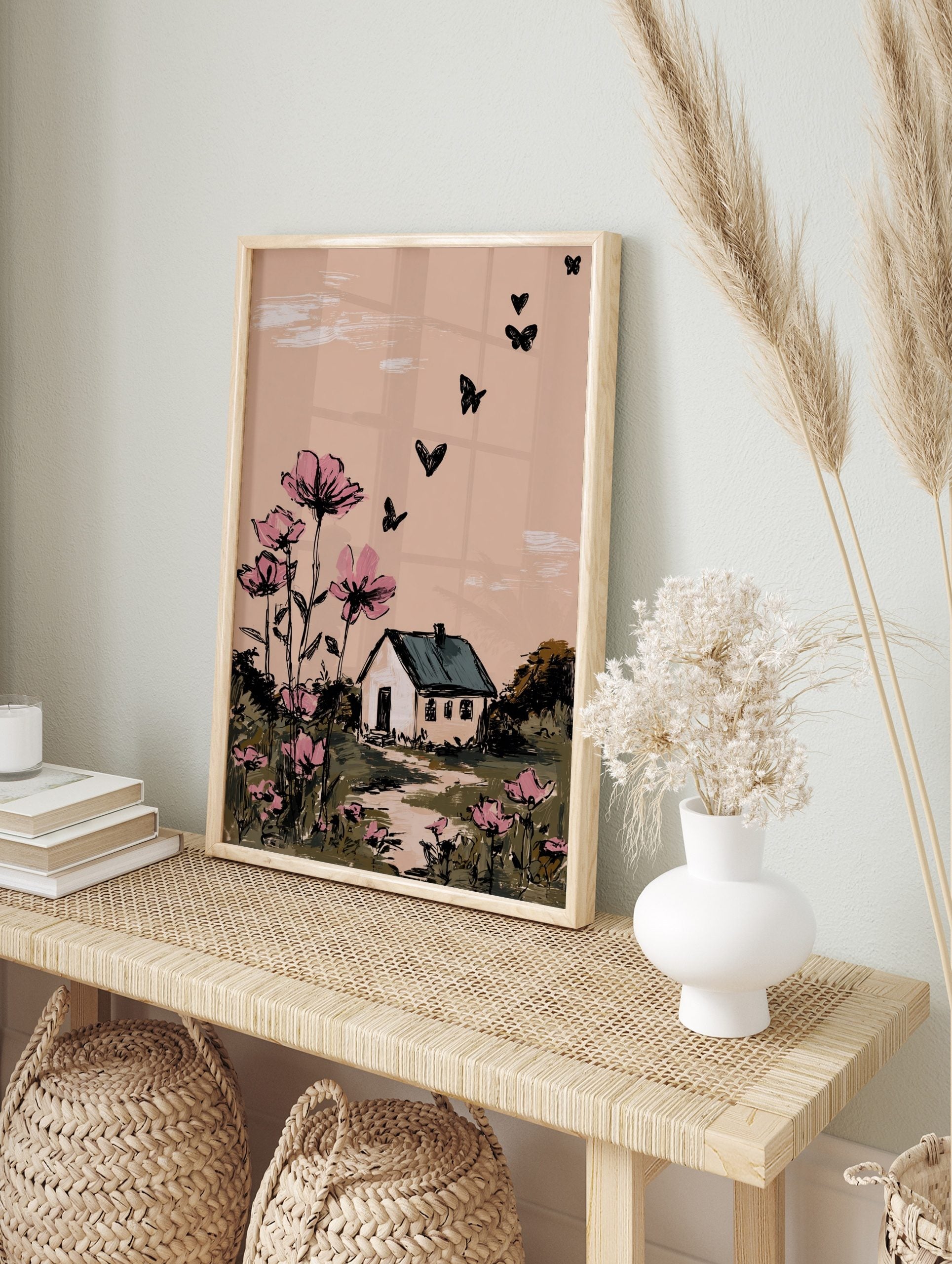 Illustrative wall art with pink cosmos flowers, a white house, and black butterflies against, in an alternate framed mockup
