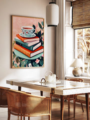 Illustrative art print of a floral teacup on a stack of books, surrounded by green leaves and pink, in a styled room mockup